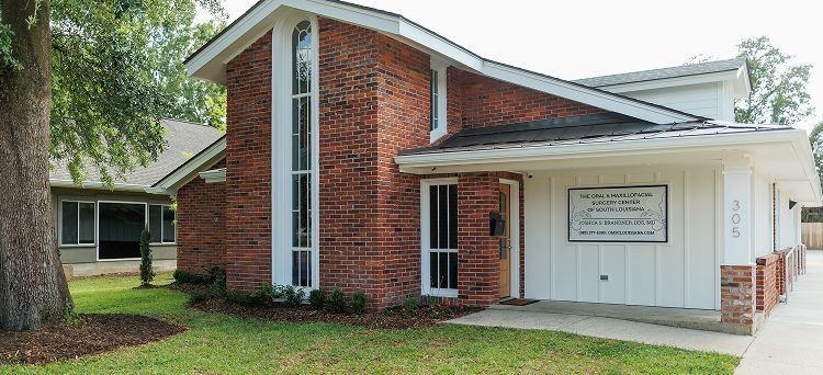 Brick building with sign and landscaped area.