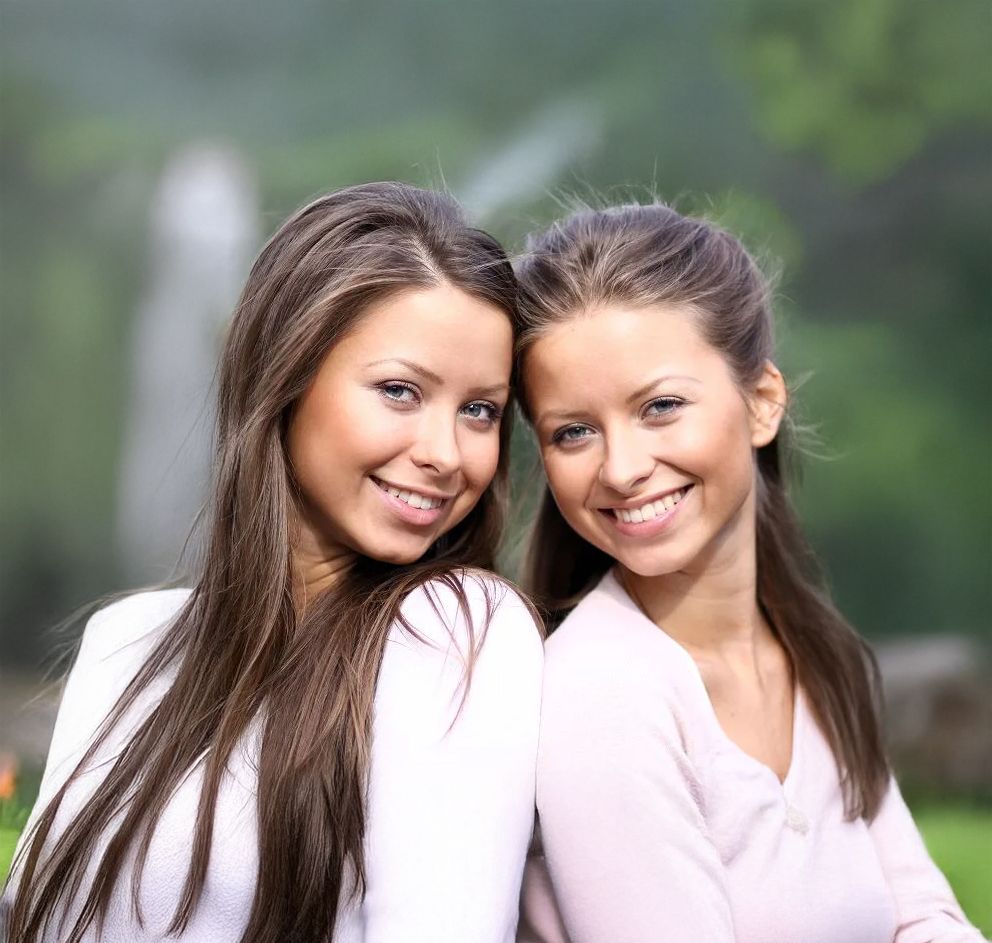 Two smiling women in a natural setting.